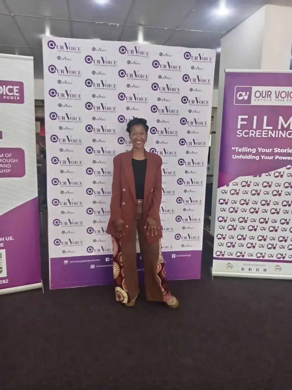 A guest at the Our Voice and film screening banners